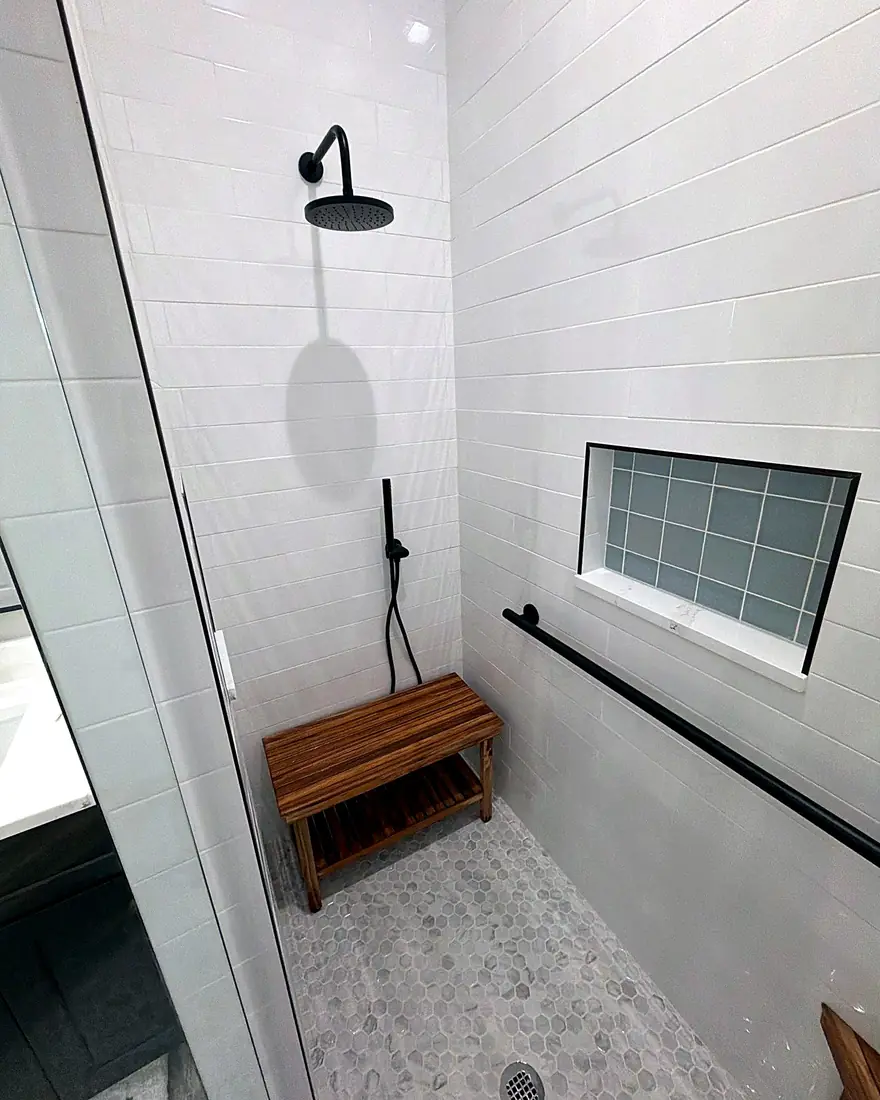 Matte black grab bar mounted on white tile in a walk-in shower with a teak bench, Lake Mary, Florida